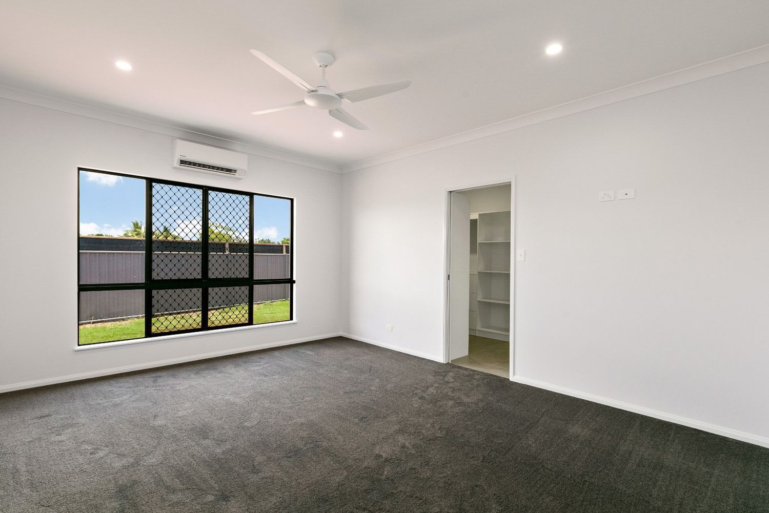 An Empty Living Room With a Ceiling Fan and a Window — Ashlee Jones Homes in Gordonvale, QLD