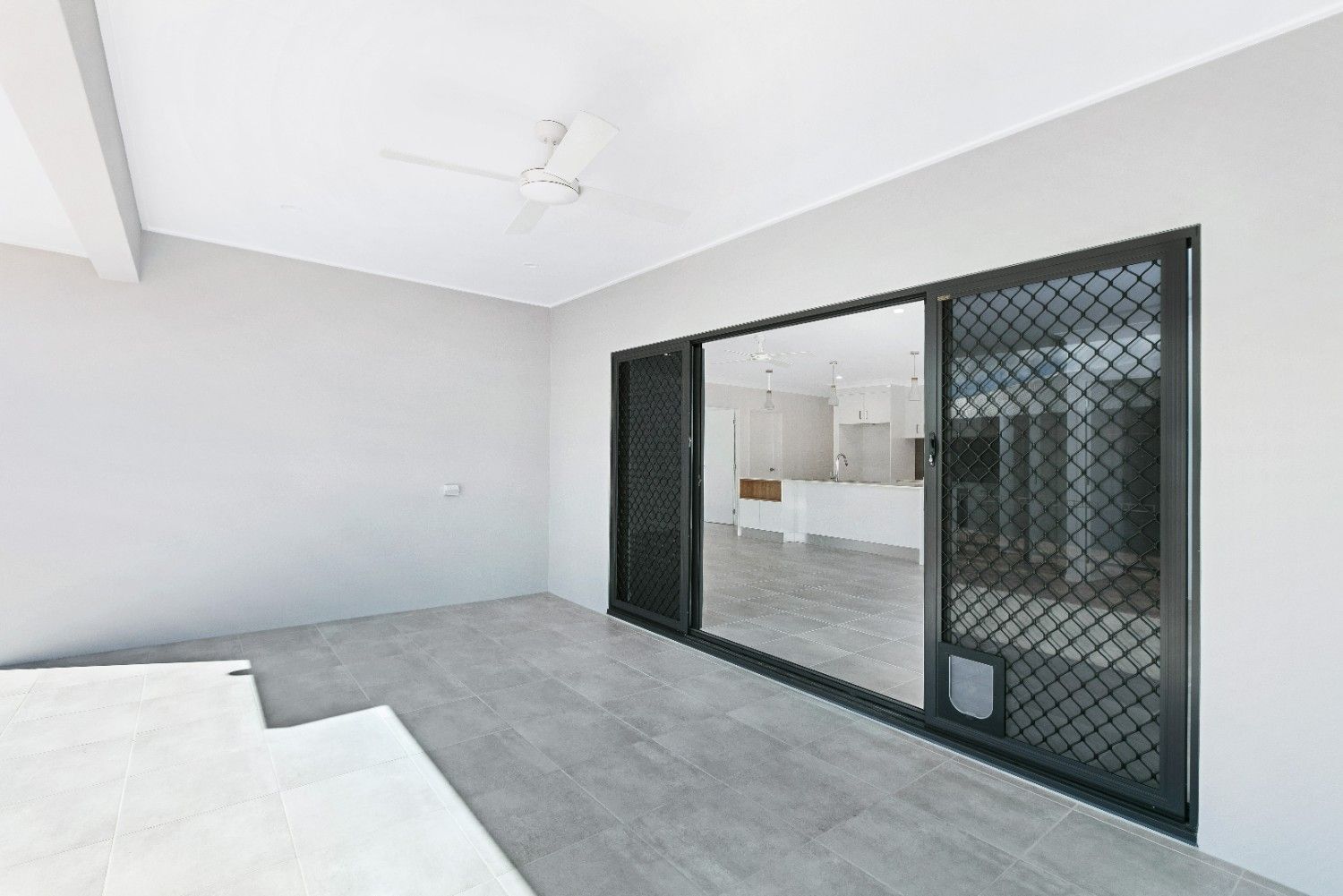 An Empty Room With Sliding Glass Doors and a Ceiling Fan — Ashlee Jones Homes in Gordonvale, QLD
