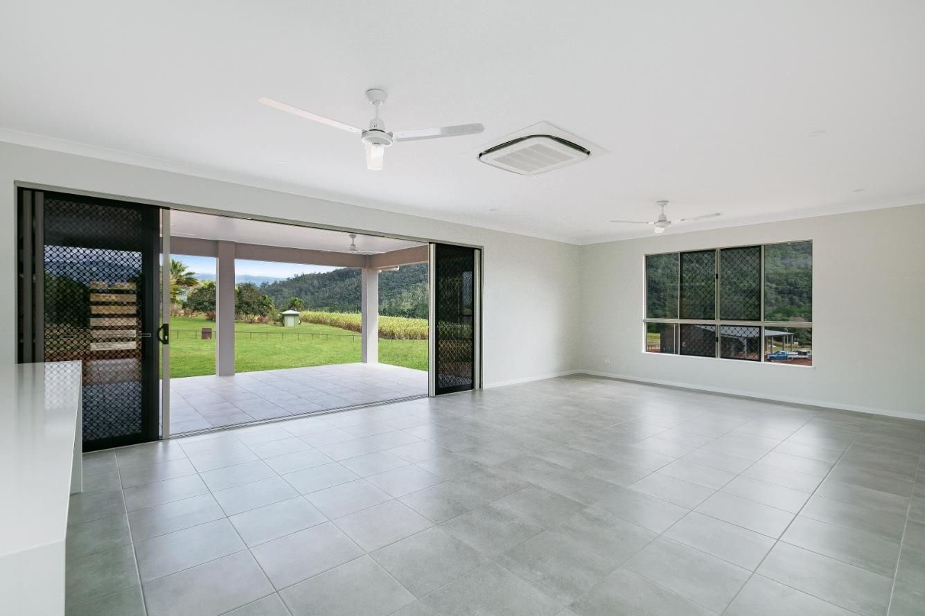 An Empty Living Room With a Ceiling Fan and Sliding Glass Doors Leading to a Patio — Ashlee Jones Homes in Gordonvale, QLD