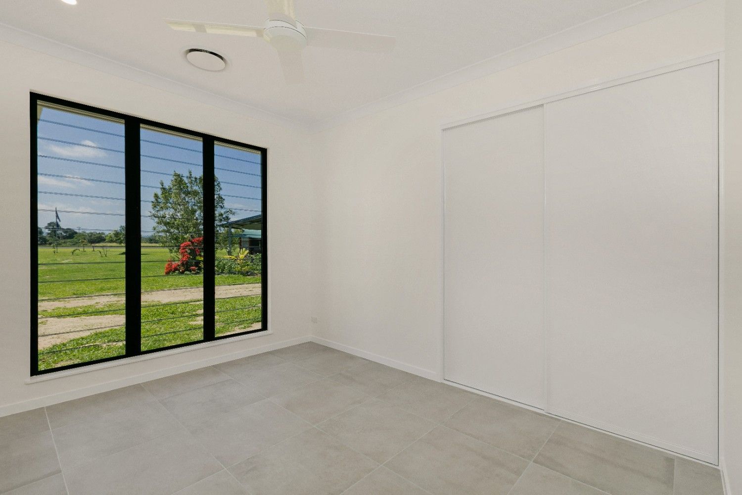 An Empty Room With a Lot of Windows and a Ceiling Fan — Ashlee Jones Homes in Gordonvale, QLD