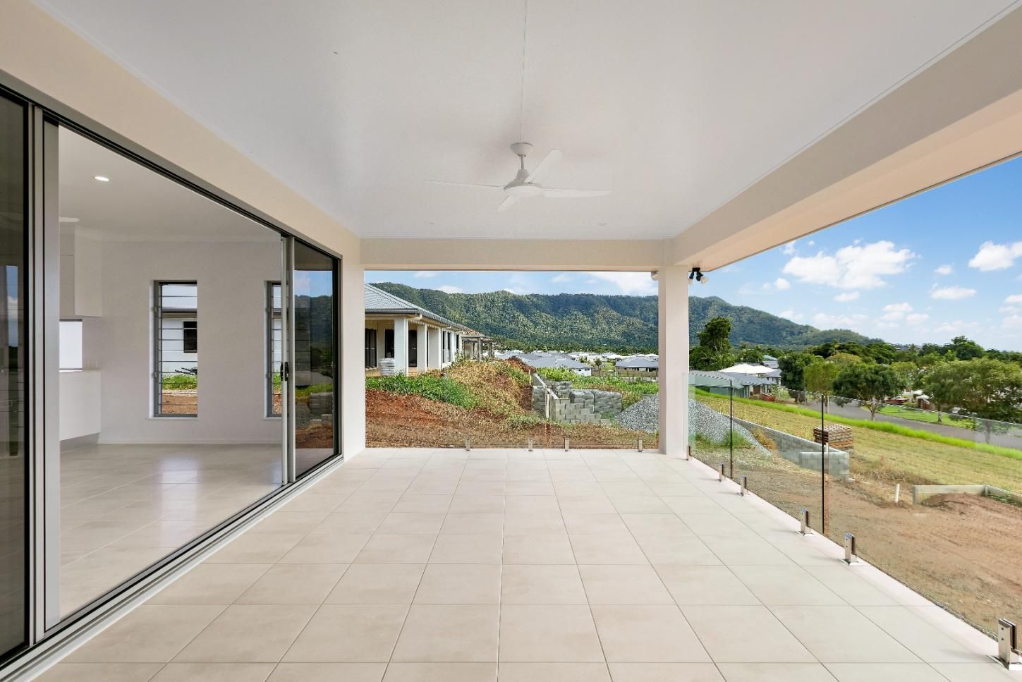 A Large Patio With Sliding Glass Doors and a View of the Mountains — Ashlee Jones Homes in Gordonvale, QLD