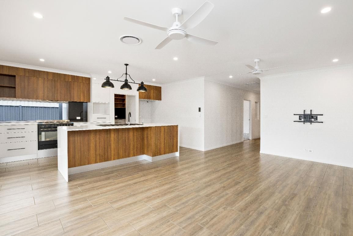 An Empty Kitchen With Wooden Floors and a Ceiling Fan — Ashlee Jones Homes in Gordonvale, QLD