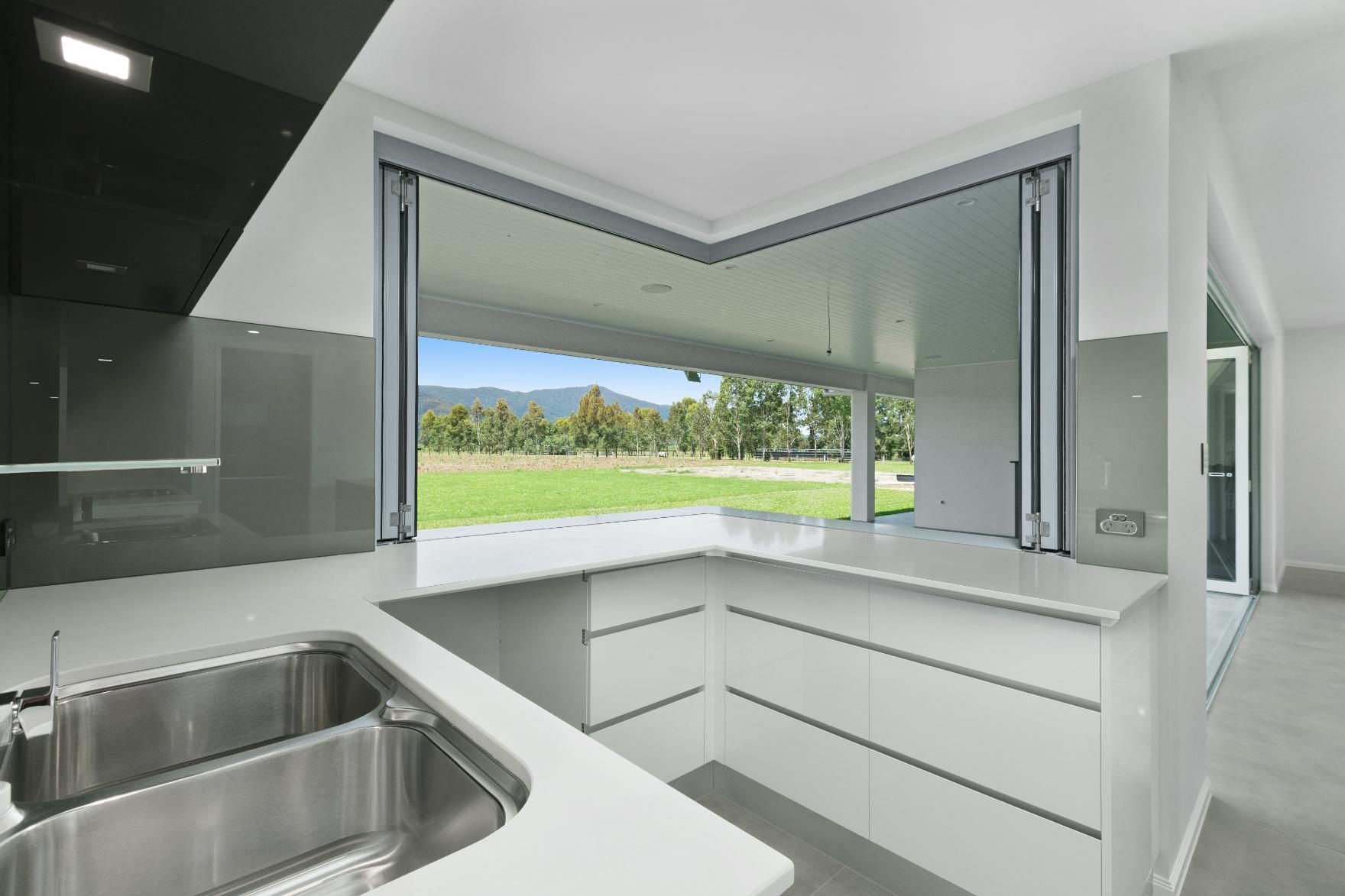 A Kitchen With a Stainless Steel Sink and a Large Window — Ashlee Jones Homes in Gordonvale, QLD