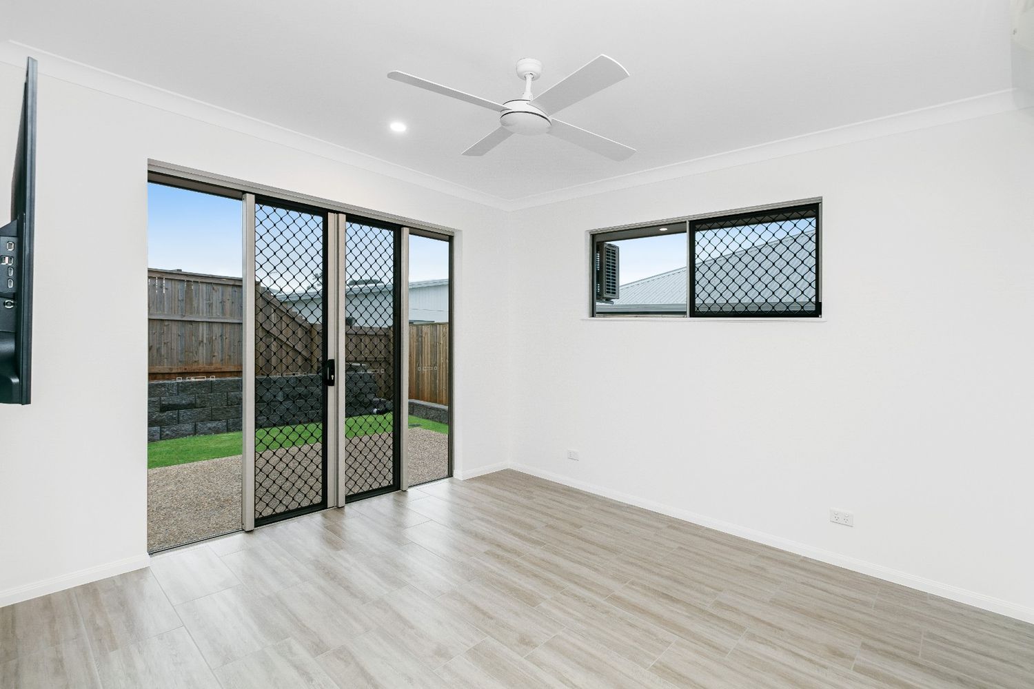 An Empty Living Room With Sliding Glass Doors and a Ceiling Fan — Ashlee Jones Homes in Gordonvale, QLD