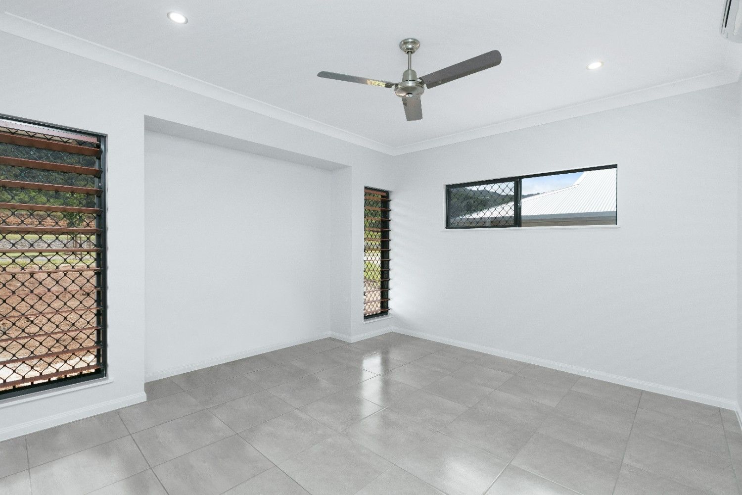 An Empty Room With a Ceiling Fan and Two Windows — Ashlee Jones Homes in Gordonvale, QLD