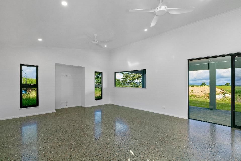 A Large Empty Room With a Ceiling Fan and Sliding Glass Doors — Ashlee Jones Homes in Gordonvale, QLD
