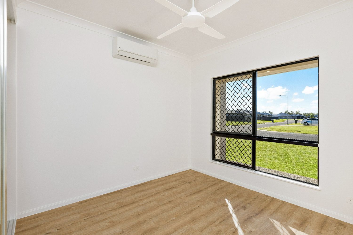 An Empty Room With a Ceiling Fan and a Large Window — Ashlee Jones Homes in Gordonvale, QLD