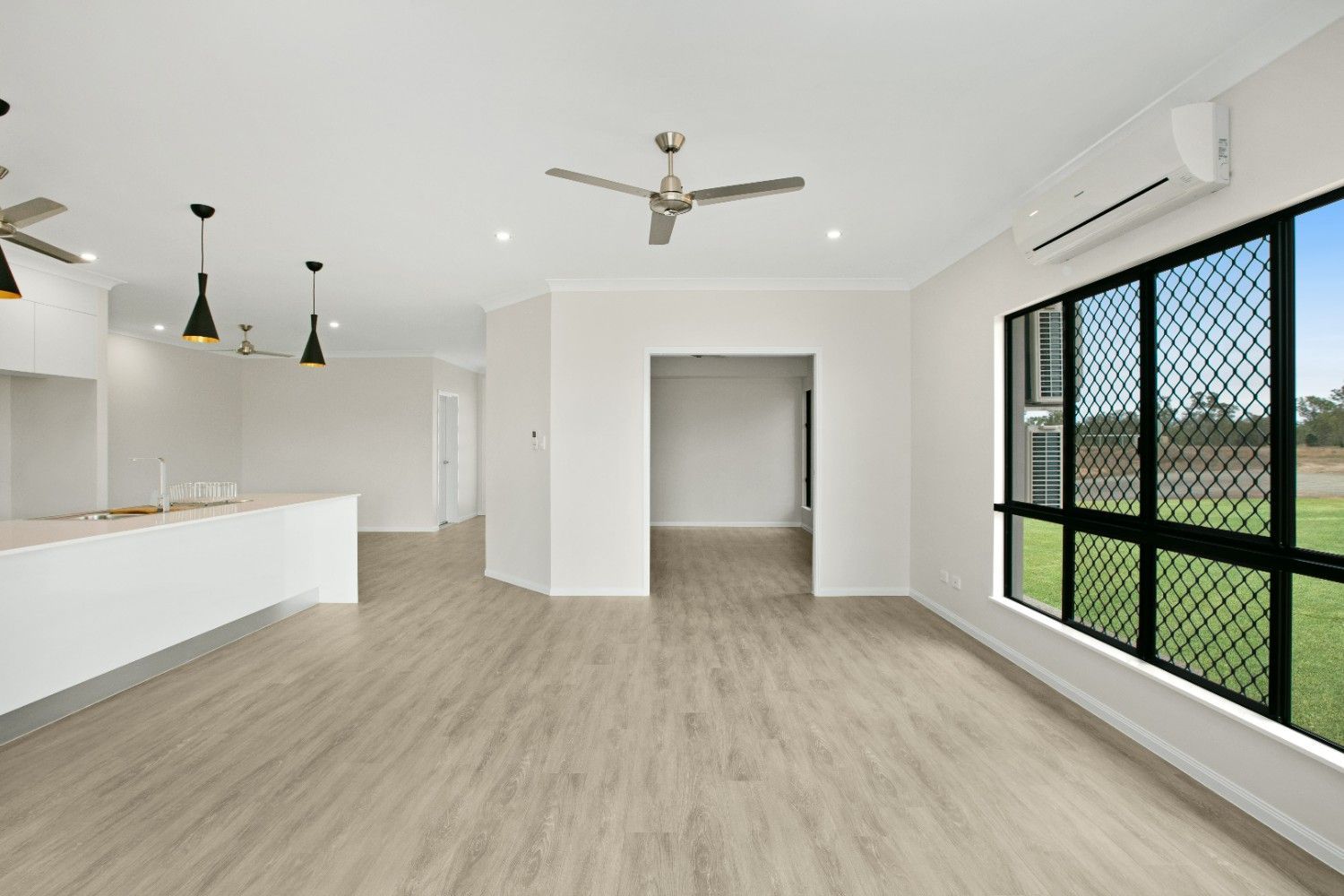 An Empty Living Room With a Ceiling Fan and a Large Window — Ashlee Jones Homes in Gordonvale, QLD