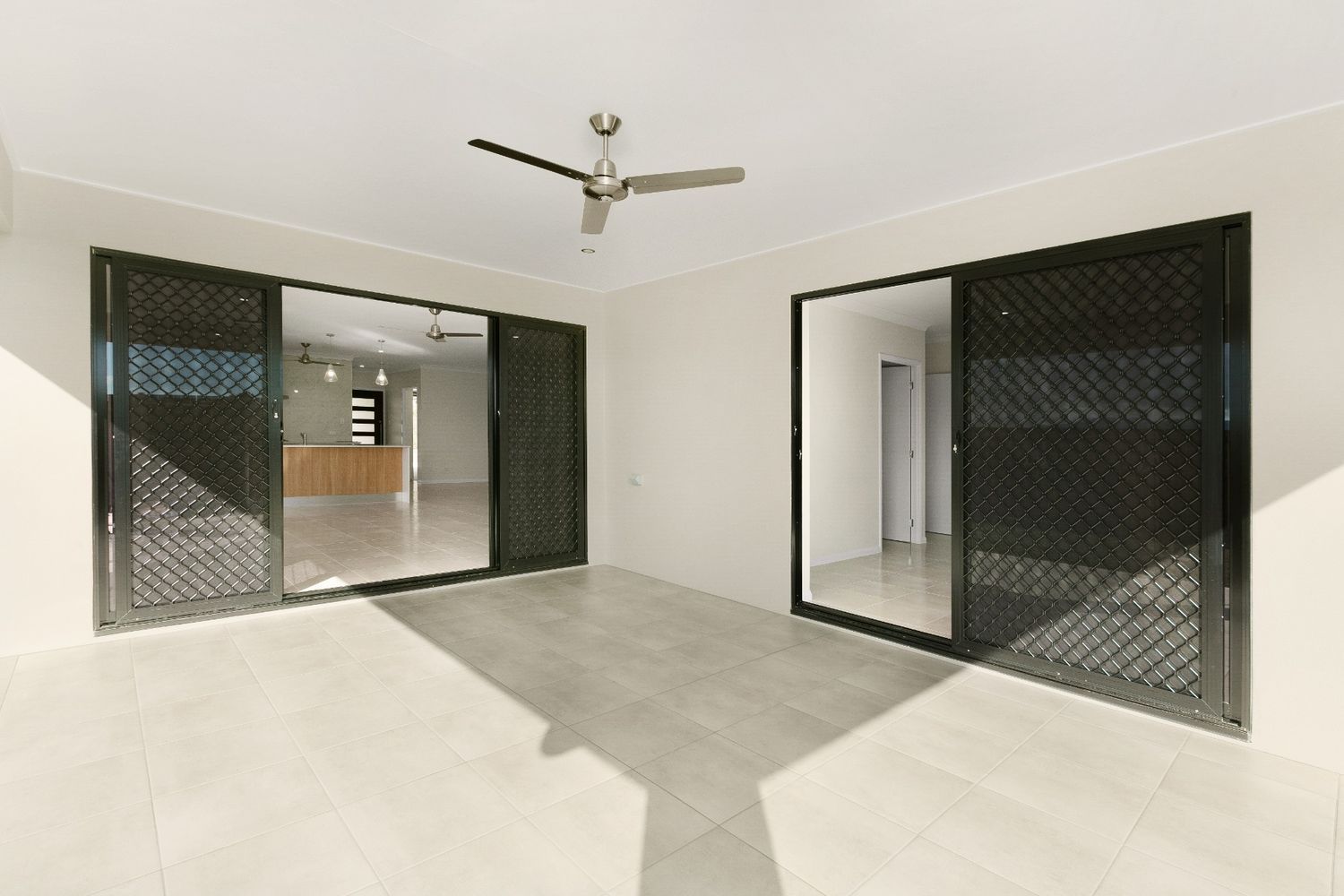 An Empty Room With Sliding Glass Doors and a Ceiling Fan — Ashlee Jones Homes in Gordonvale, QLD