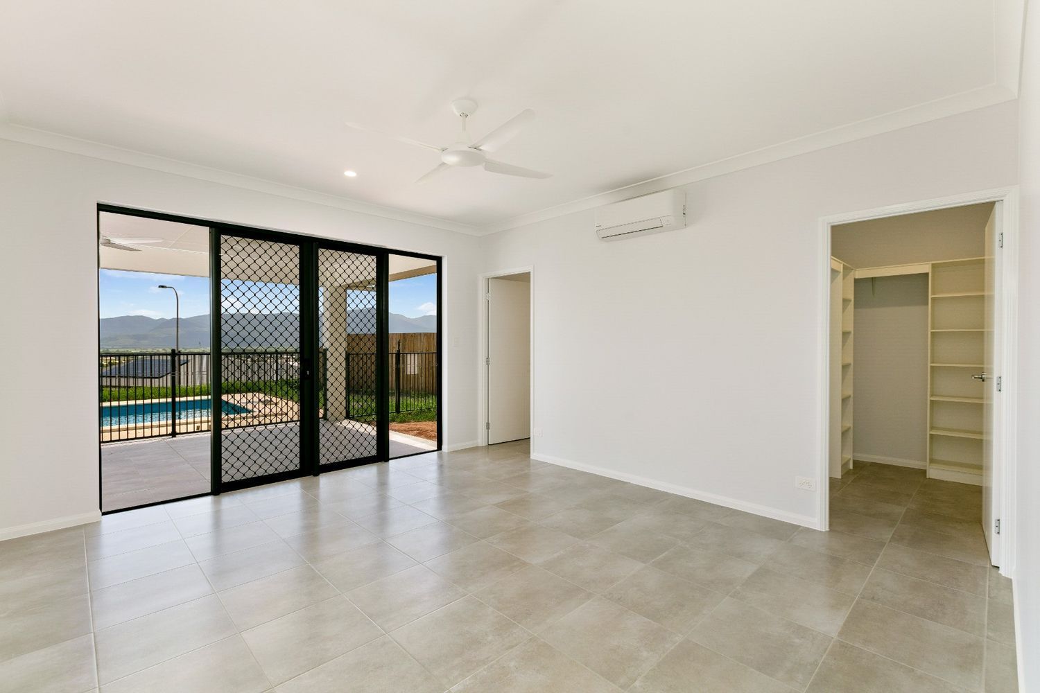 An Empty Living Room With Sliding Glass Doors Leading to a Pool — Ashlee Jones Homes in Gordonvale, QLD