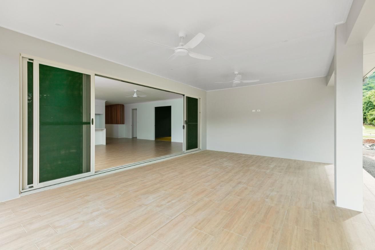 A Large Empty Room With Sliding Glass Doors and a Ceiling Fan — Ashlee Jones Homes in Gordonvale, QLD