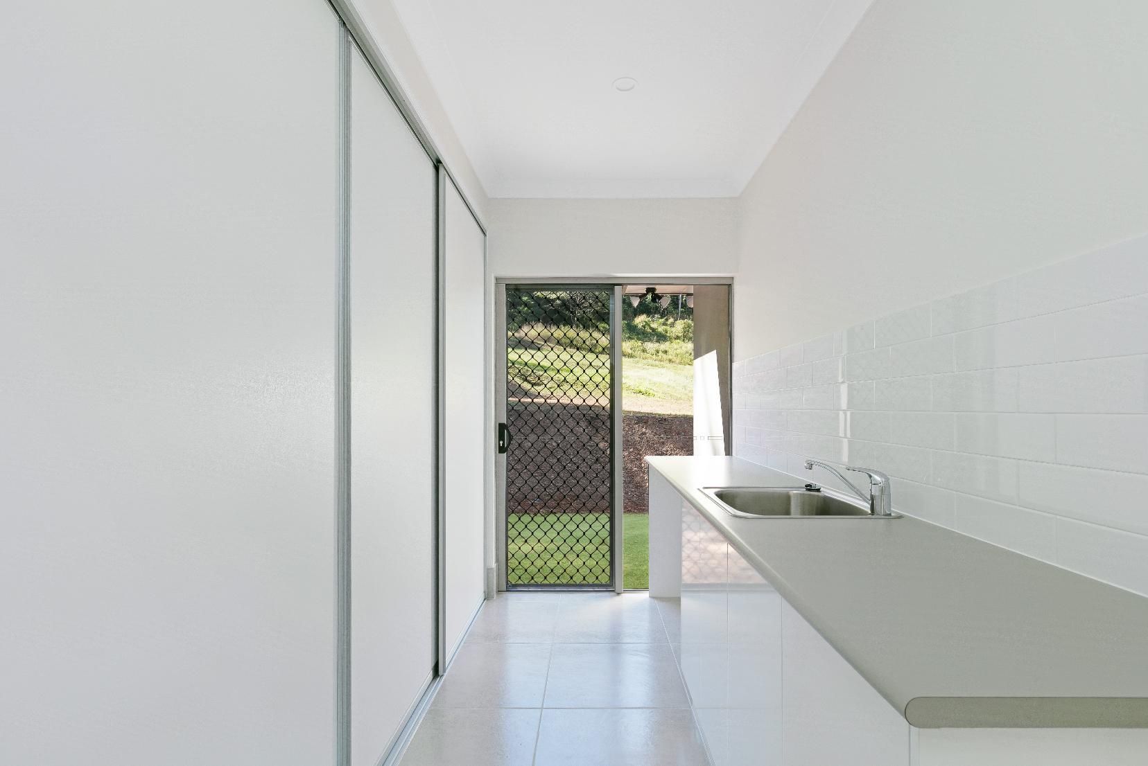 An Empty Kitchen With a Sink and a Sliding Glass Door — Ashlee Jones Homes in Gordonvale, QLD