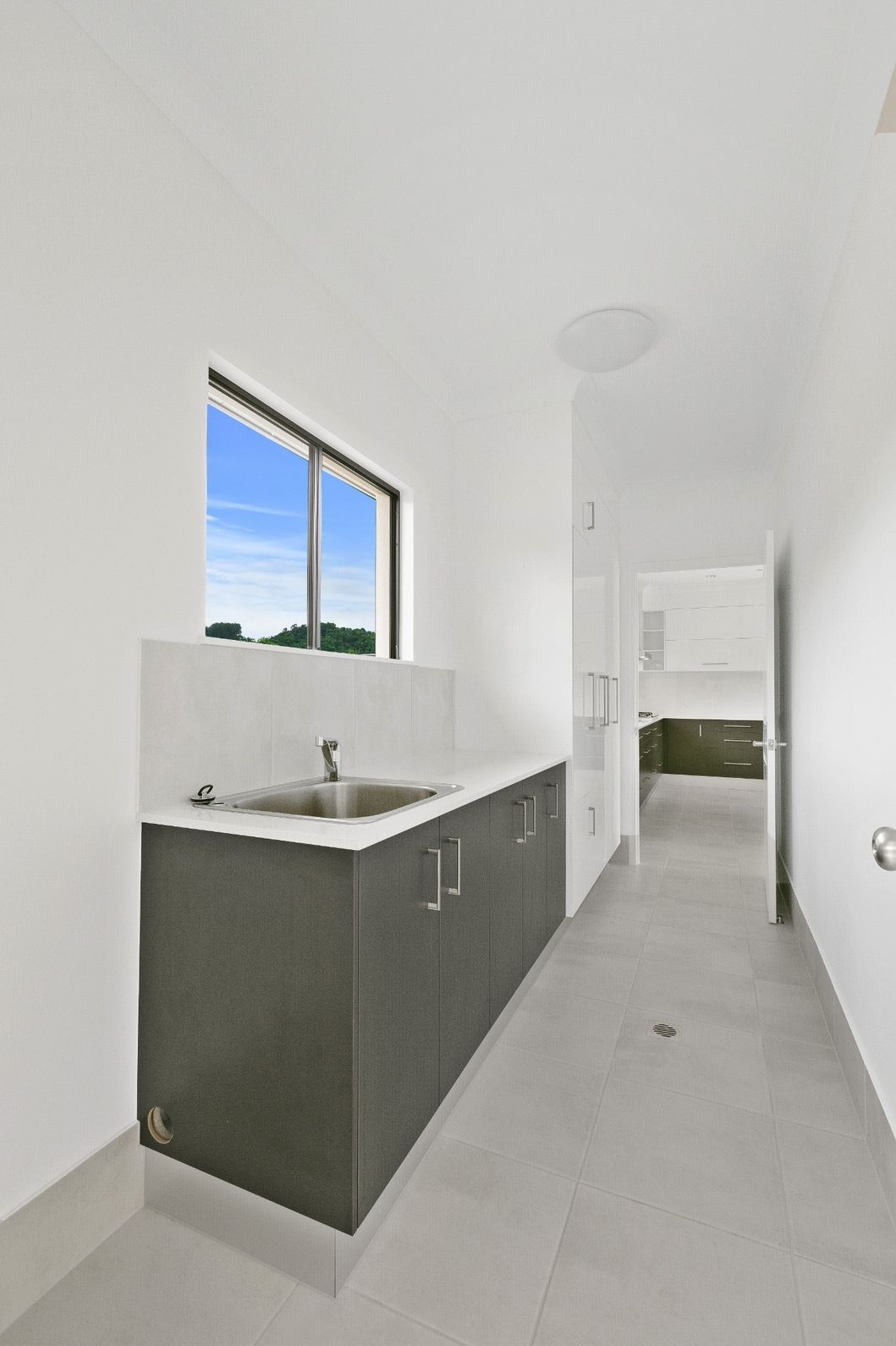 A Kitchen With a Sink , Cabinets and a Window — Ashlee Jones Homes in Gordonvale, QLD