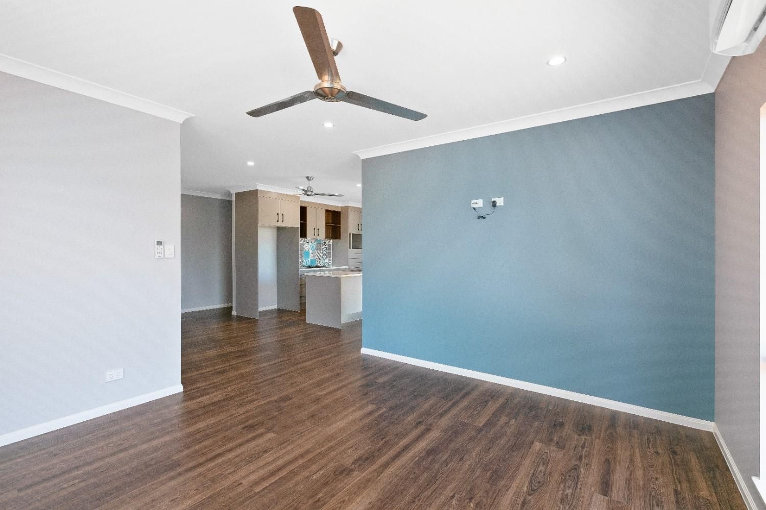 An Empty Living Room With Hardwood Floors and a Ceiling Fan — Ashlee Jones Homes in Gordonvale, QLD