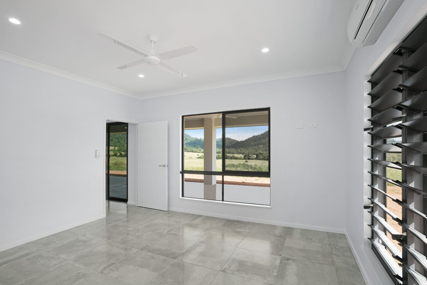 An Empty Room With a Ceiling Fan and Two Windows — Ashlee Jones Homes in Gordonvale, QLD