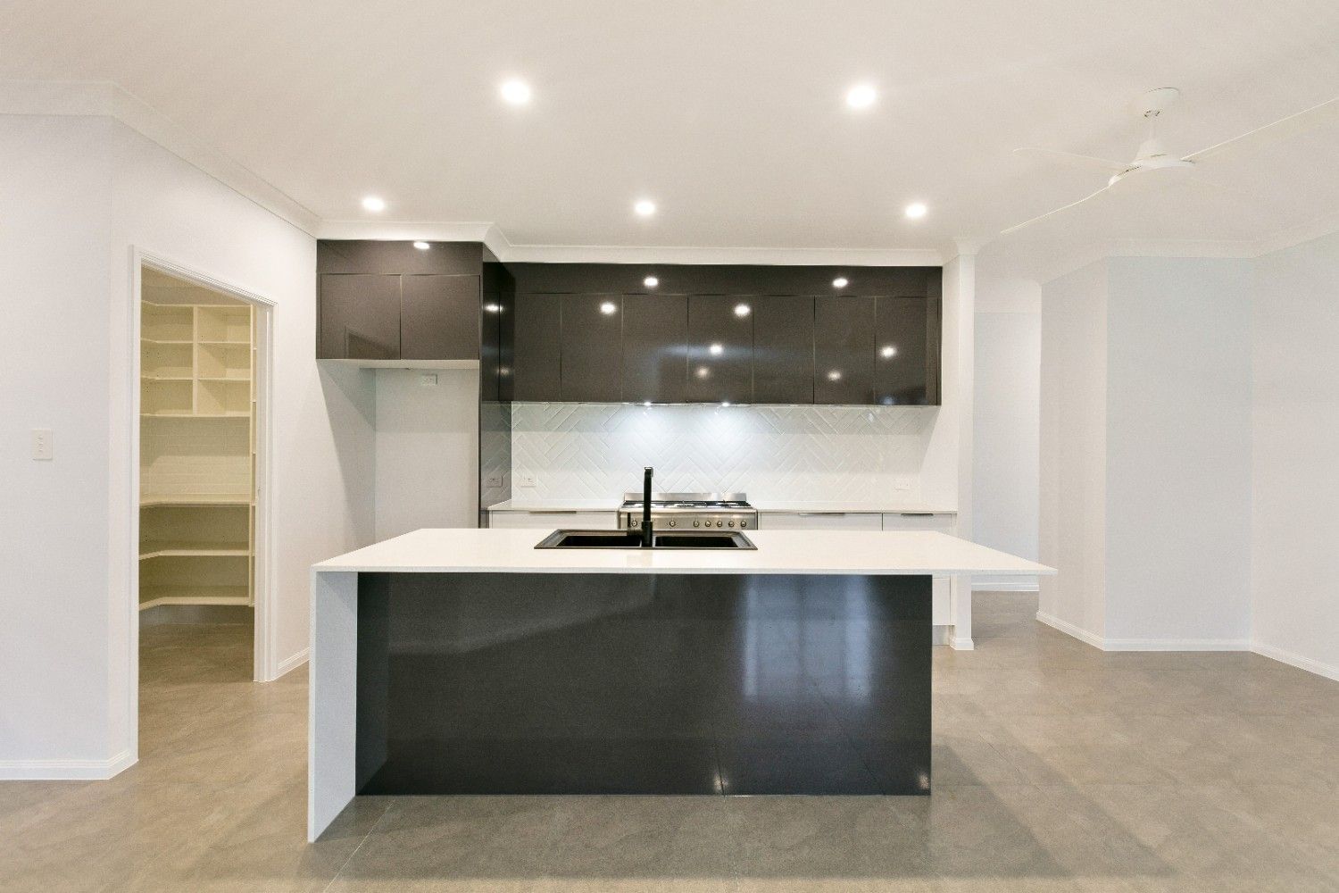 An Empty Kitchen With a Large Island and a Sink — Ashlee Jones Homes in Gordonvale, QLD