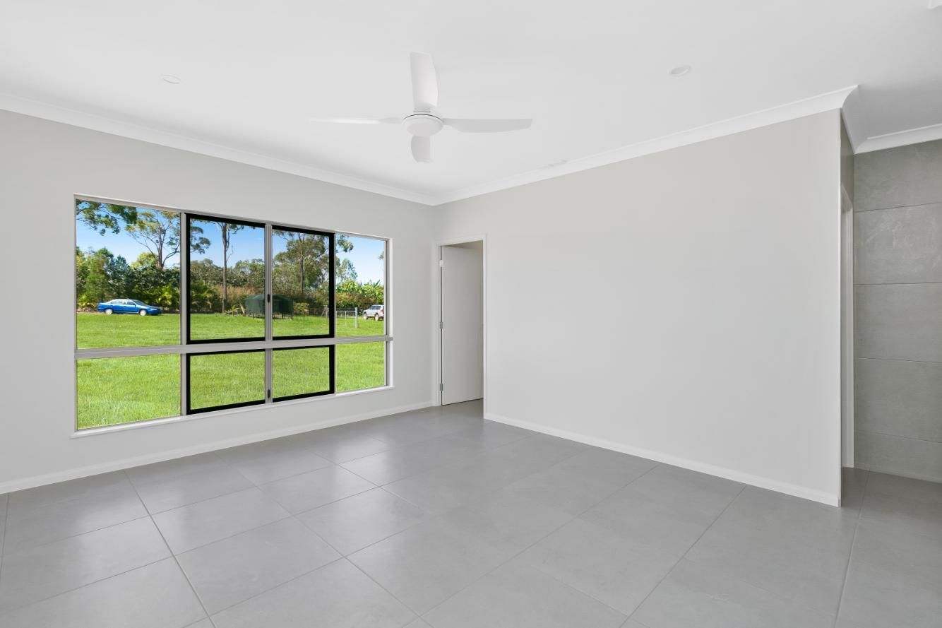 An Empty Living Room With a Ceiling Fan and Two Windows — Ashlee Jones Homes in Gordonvale, QLD