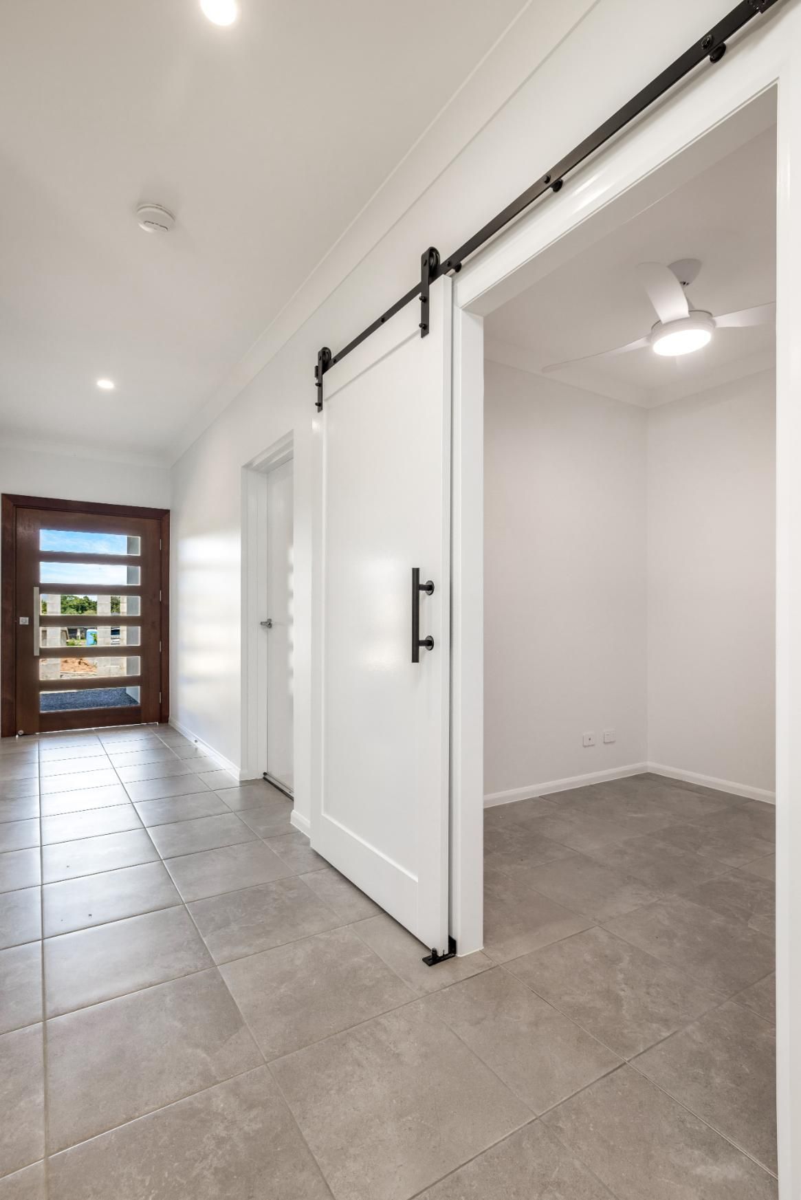An Empty Hallway With a Sliding Barn Door — Ashlee Jones Homes in Gordonvale, QLD