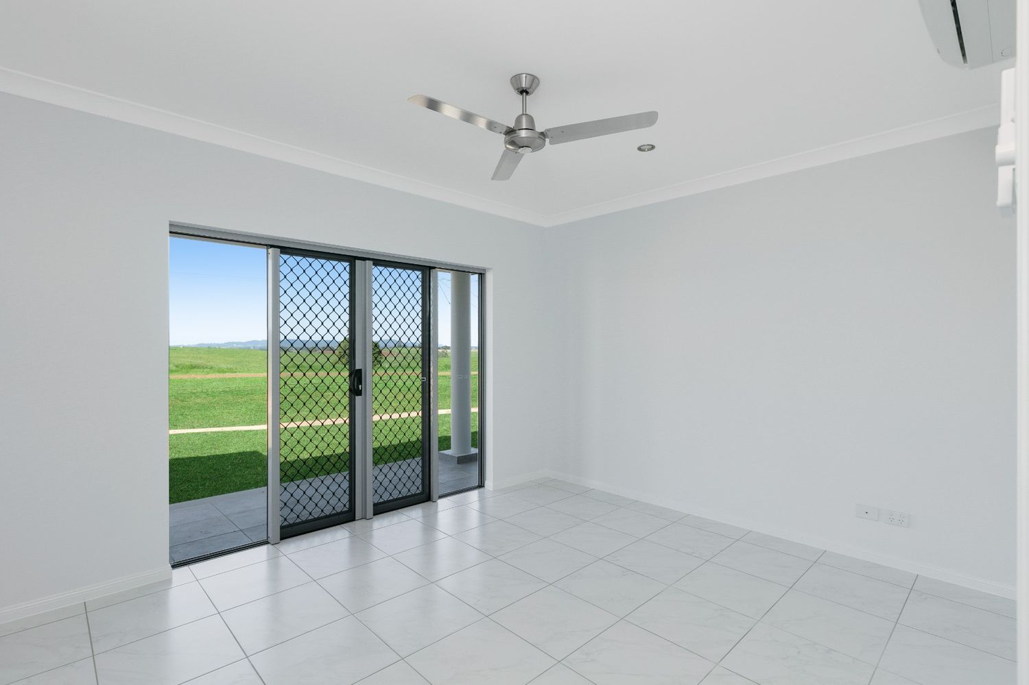 An Empty Room With Sliding Glass Doors and a Ceiling Fan — Ashlee Jones Homes in Gordonvale, QLD