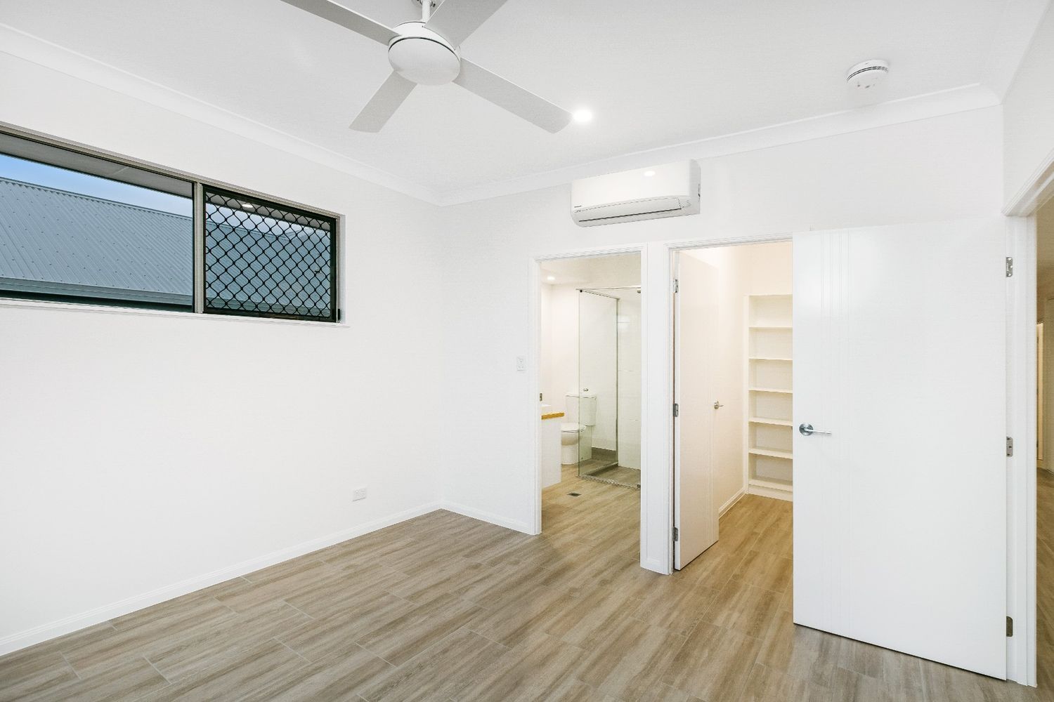 An Empty Bedroom With a Ceiling Fan and a Bathroom — Ashlee Jones Homes in Gordonvale, QLD