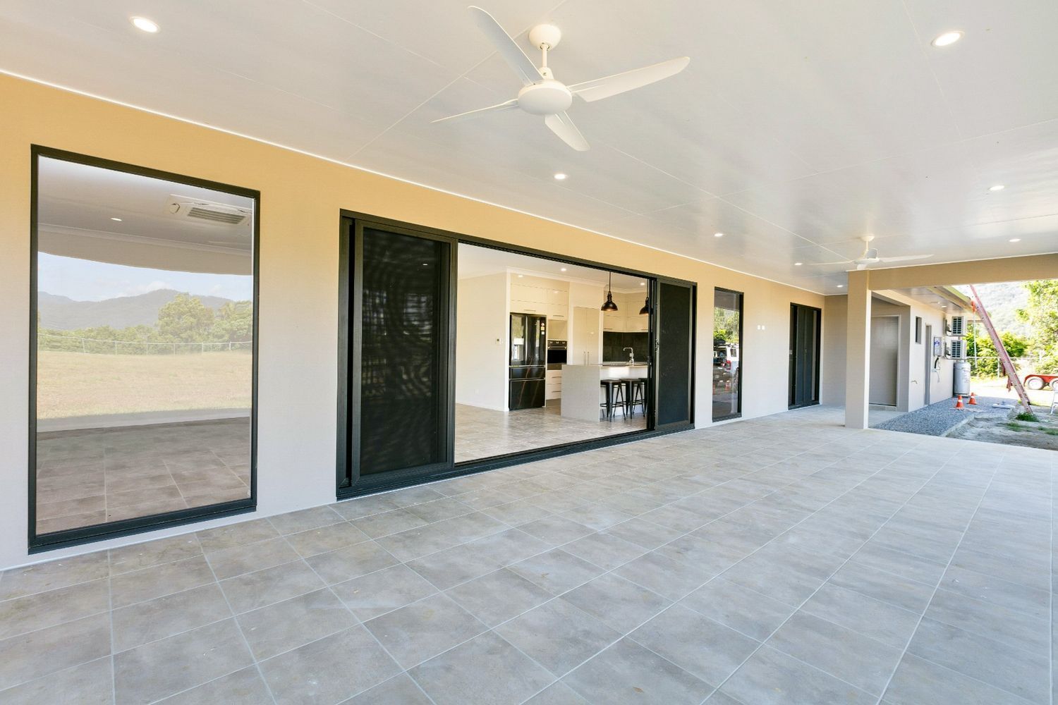 A Large Patio With Sliding Glass Doors and a Ceiling Fan — Ashlee Jones Homes in Gordonvale, QLD
