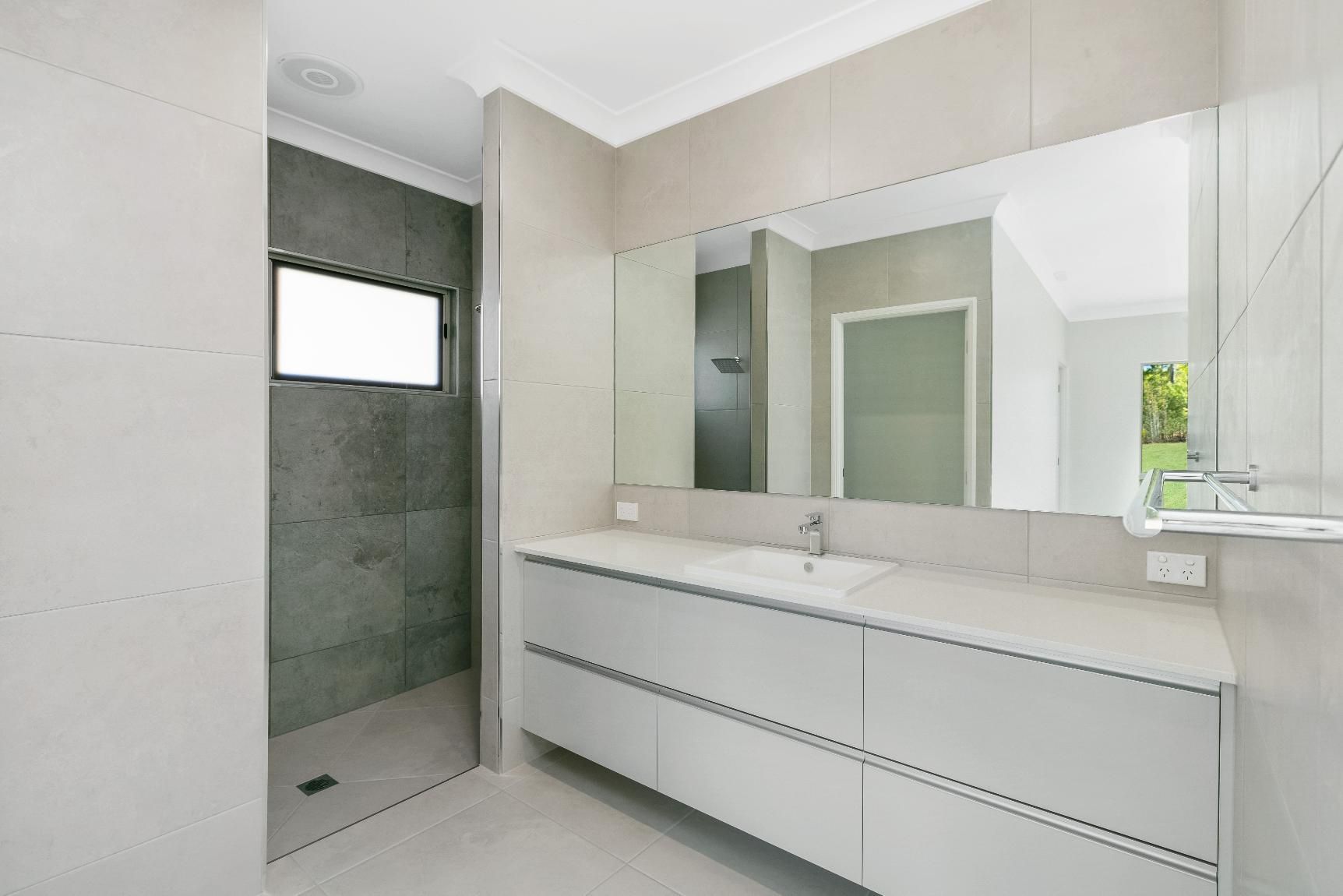 A Bathroom With a Sink, Mirror and Walk in Shower — Ashlee Jones Homes in Gordonvale, QLD