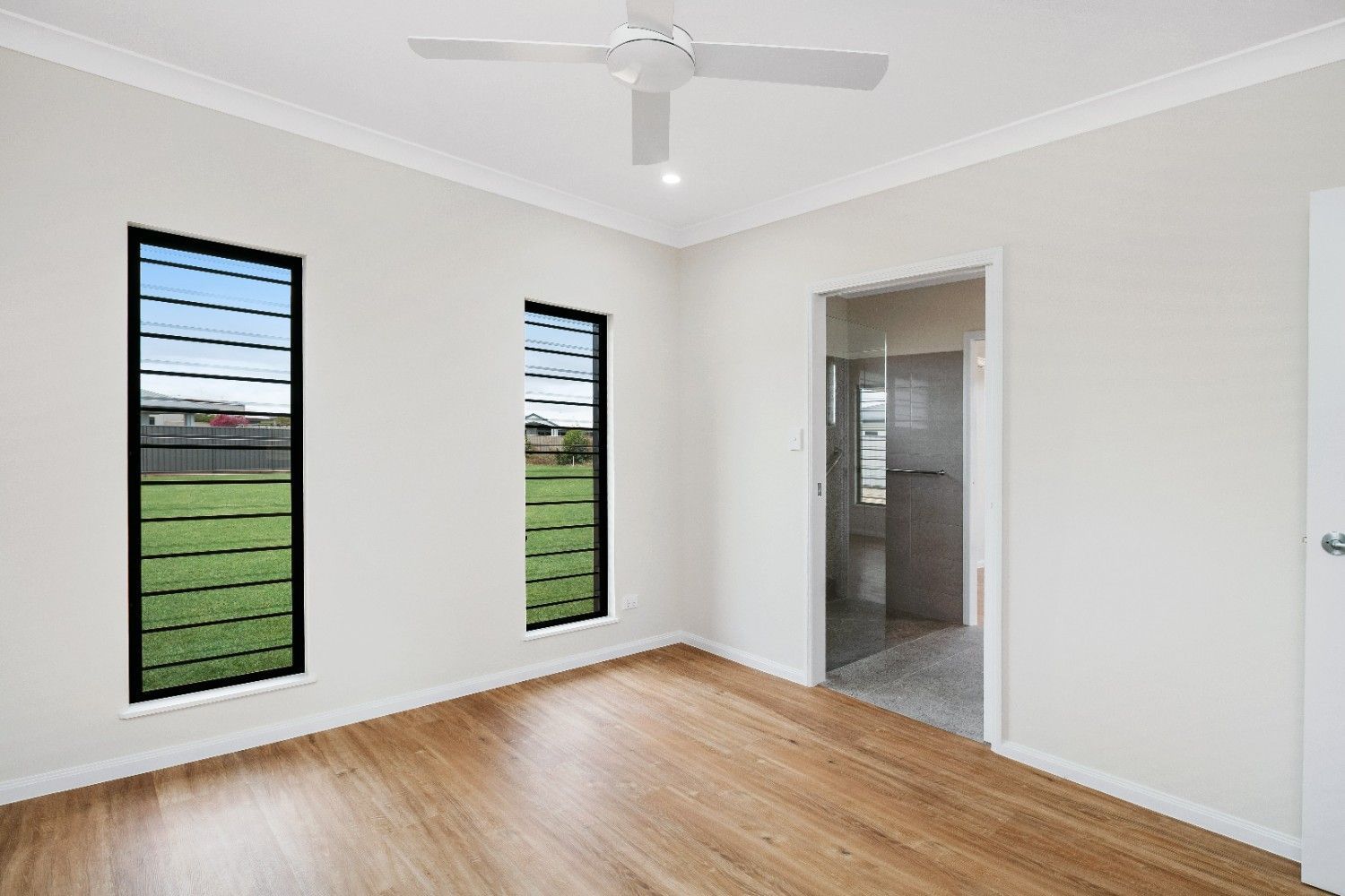 An Empty Room With a Ceiling Fan and Two Windows — Ashlee Jones Homes in Gordonvale, QLD