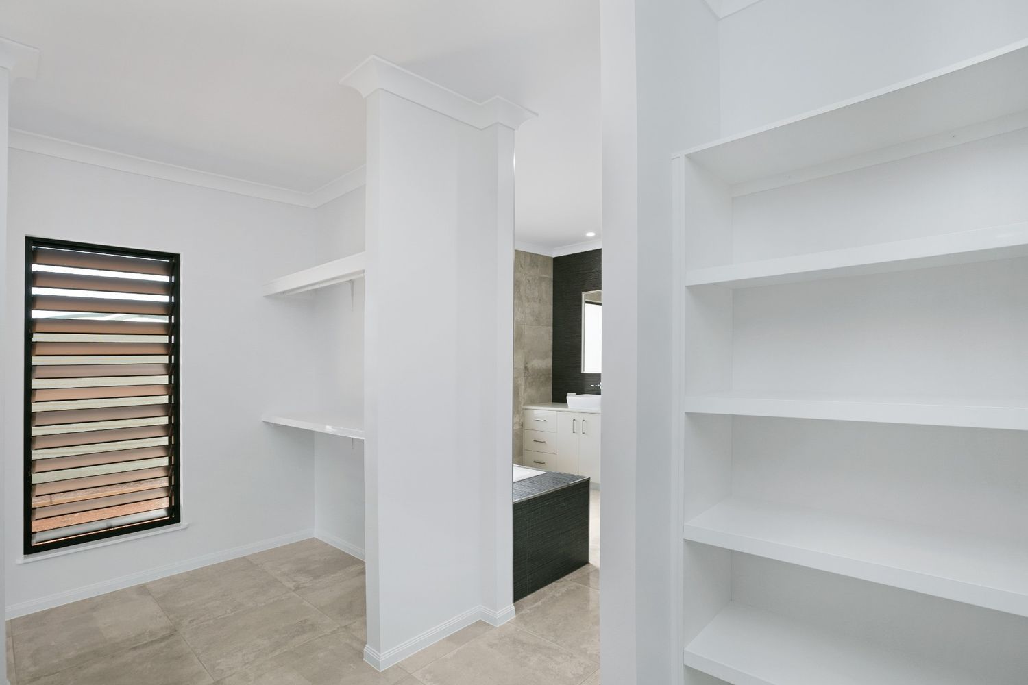 A Walk in Closet With Lots of Shelves and a Window — Ashlee Jones Homes in Gordonvale, QLD