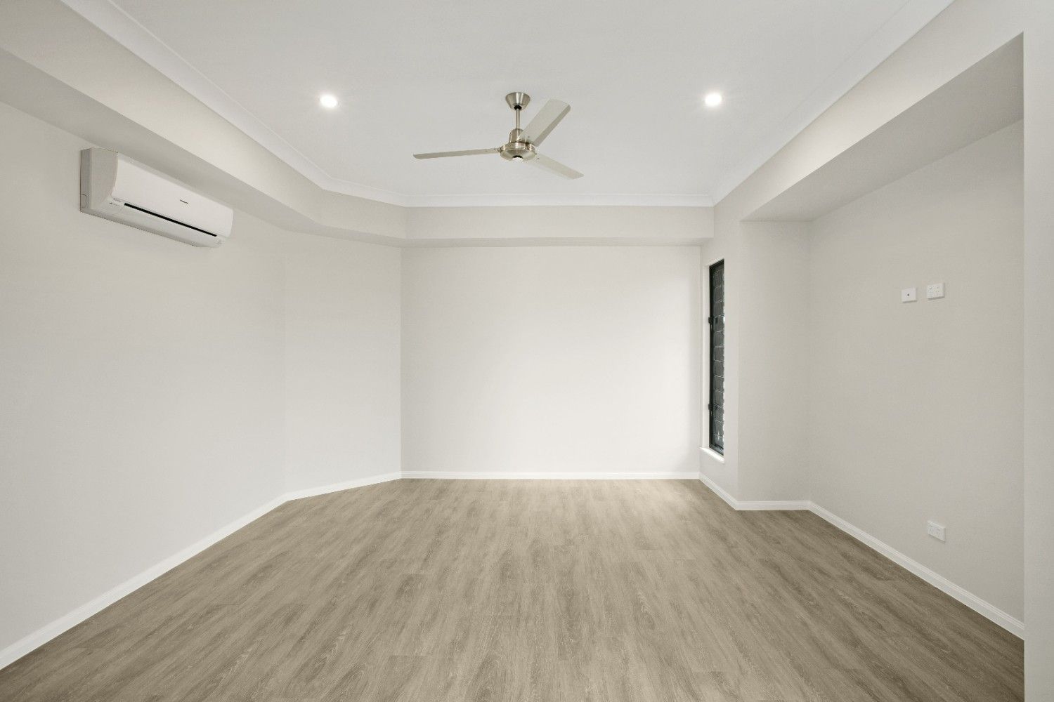 An Empty Room With a Ceiling Fan and Air Conditioner — Ashlee Jones Homes in Gordonvale, QLD