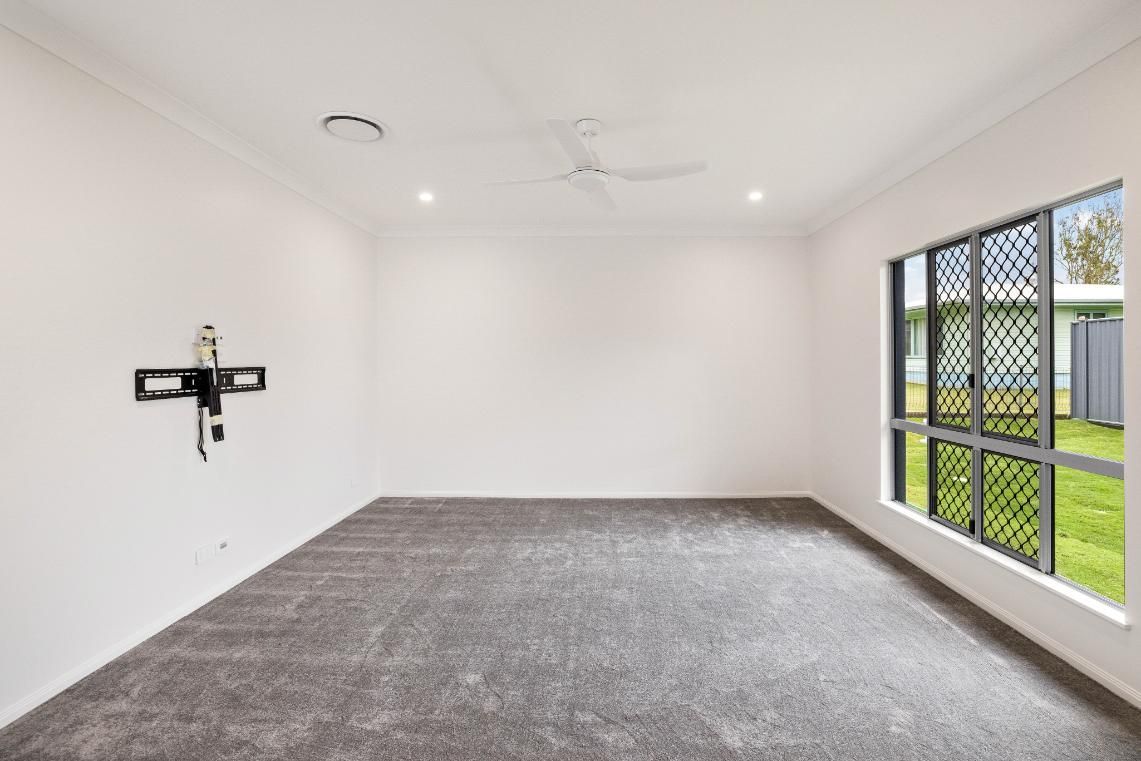An Empty Living Room With a Flat Screen Tv Mounted on the Wall — Ashlee Jones Homes in Gordonvale, QLD