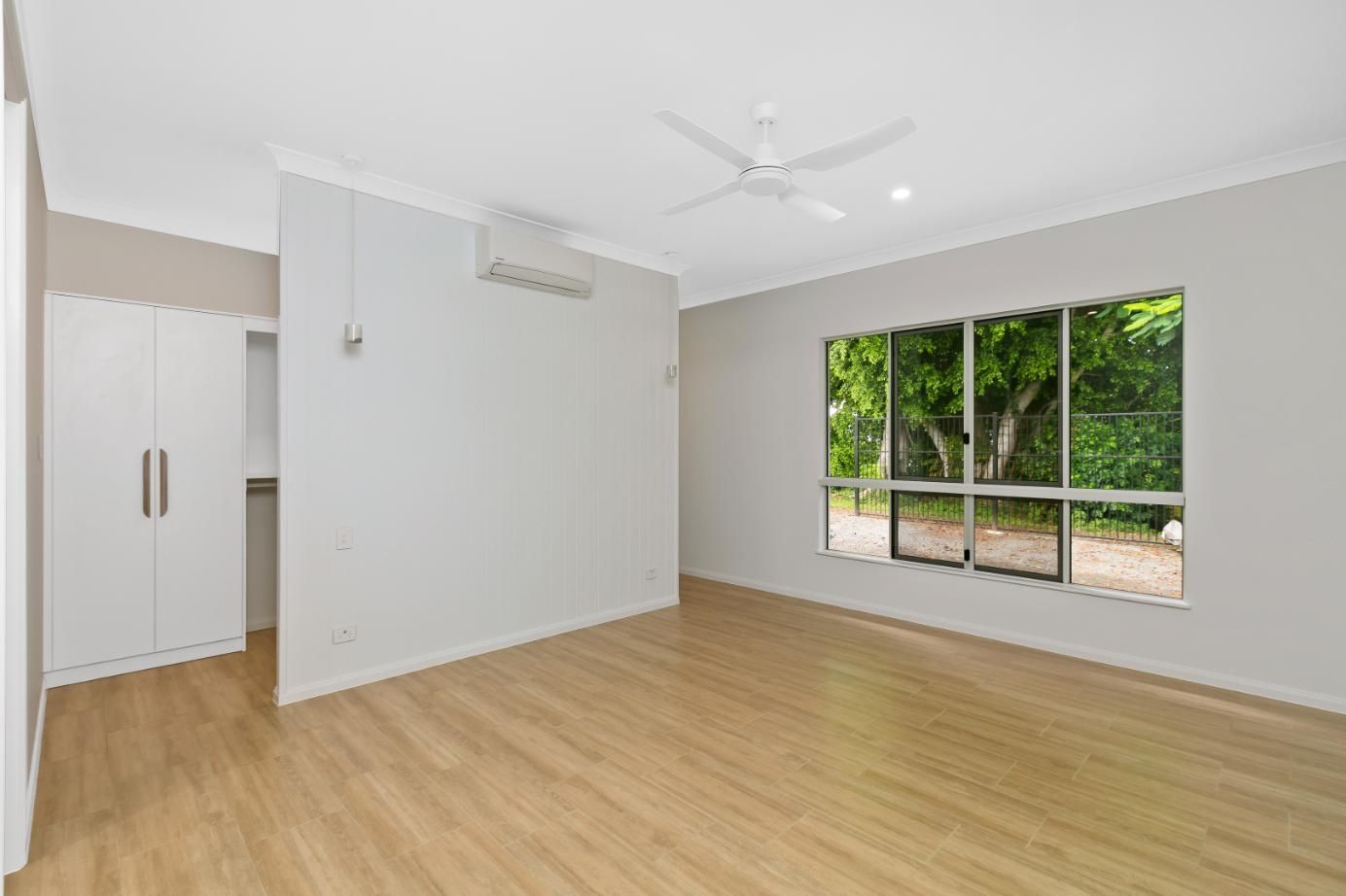 An Empty Living Room With Hardwood Floors and a Ceiling Fan — Ashlee Jones Homes in Gordonvale, QLD