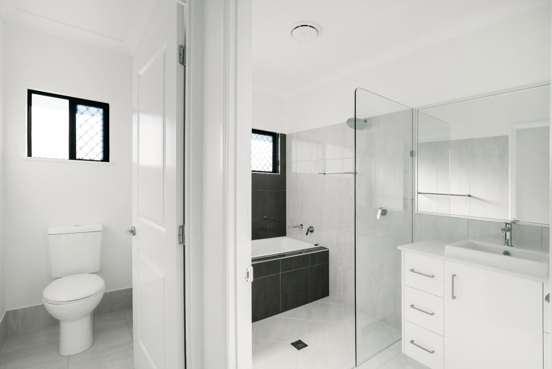 A Bathroom With a Toilet, Sink and Bathtub — Ashlee Jones Homes in Gordonvale, QLD