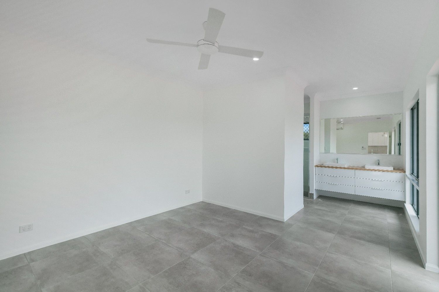 An Empty Bedroom With a Ceiling Fan and a Bathroom — Ashlee Jones Homes in Gordonvale, QLD