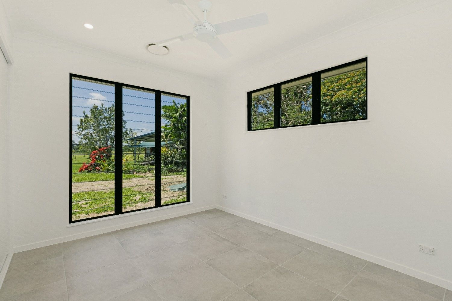 An Empty Room With Three Windows and a Ceiling Fan — Ashlee Jones Homes in Gordonvale, QLD