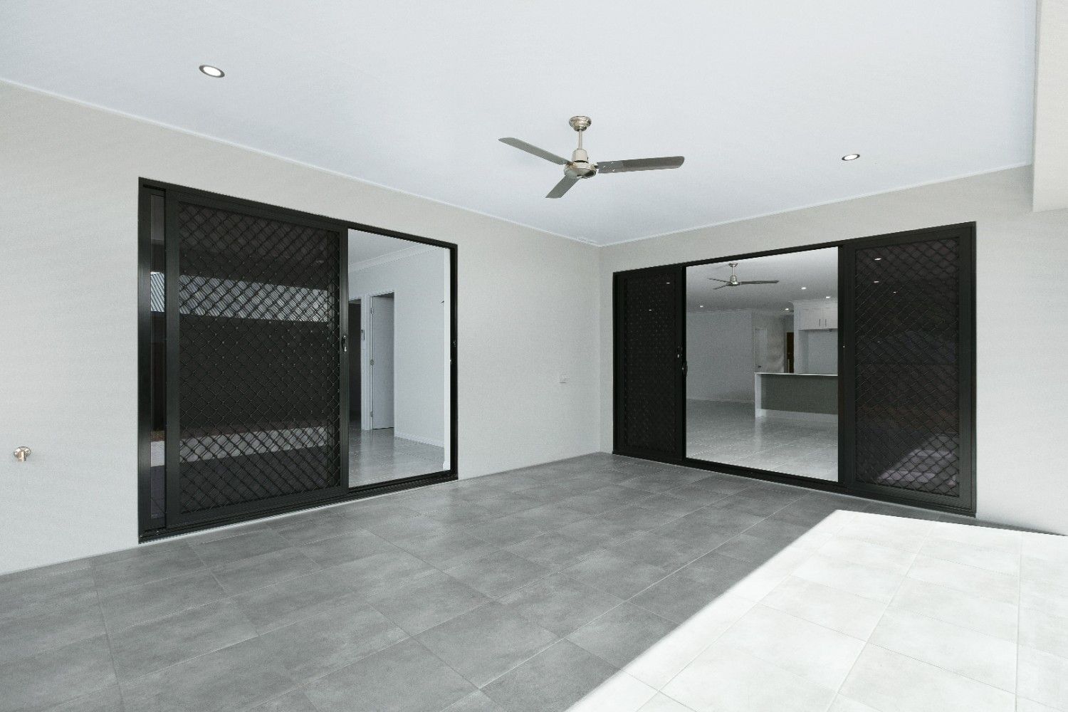 An Empty Room With a Ceiling Fan and Sliding Glass Doors — Ashlee Jones Homes in Gordonvale, QLD