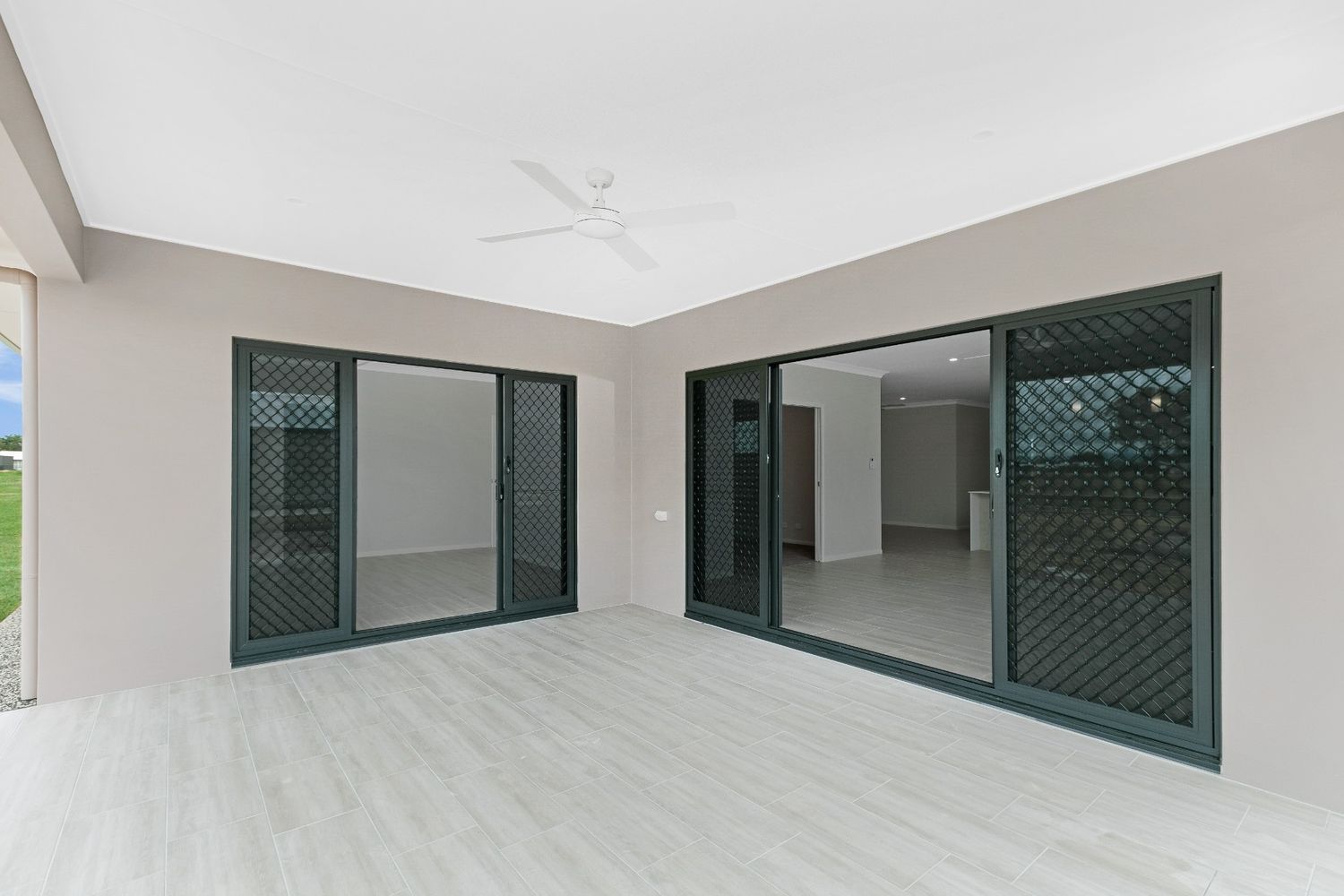 An Empty Room With Sliding Glass Doors and a Ceiling Fan — Ashlee Jones Homes in Gordonvale, QLD