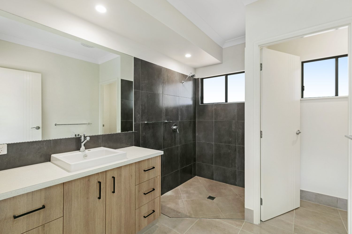 A Bathroom With a Sink, Mirror and Walk in Shower — Ashlee Jones Homes in Gordonvale, QLD