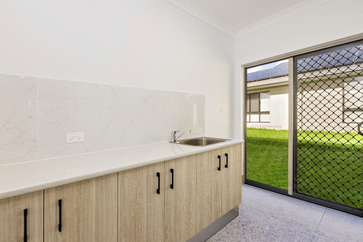 A Kitchen With Wooden Cabinets, a Sink, and a Sliding Glass Door — Ashlee Jones Homes in Gordonvale, QLD