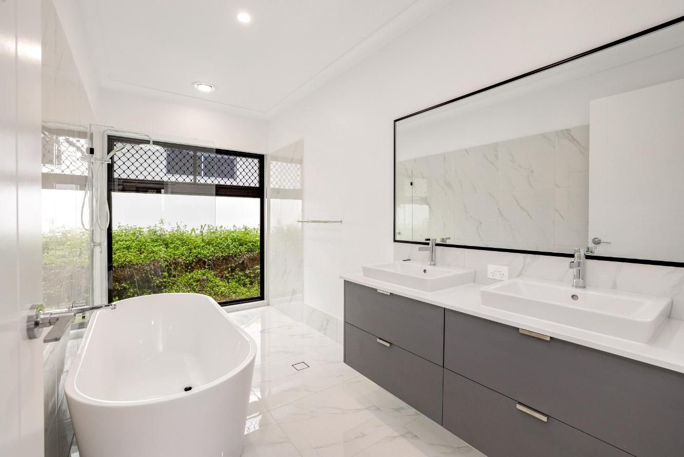 A Bathroom With a Bathtub, Sinks and a Large Mirror — Ashlee Jones Homes in Gordonvale, QLD