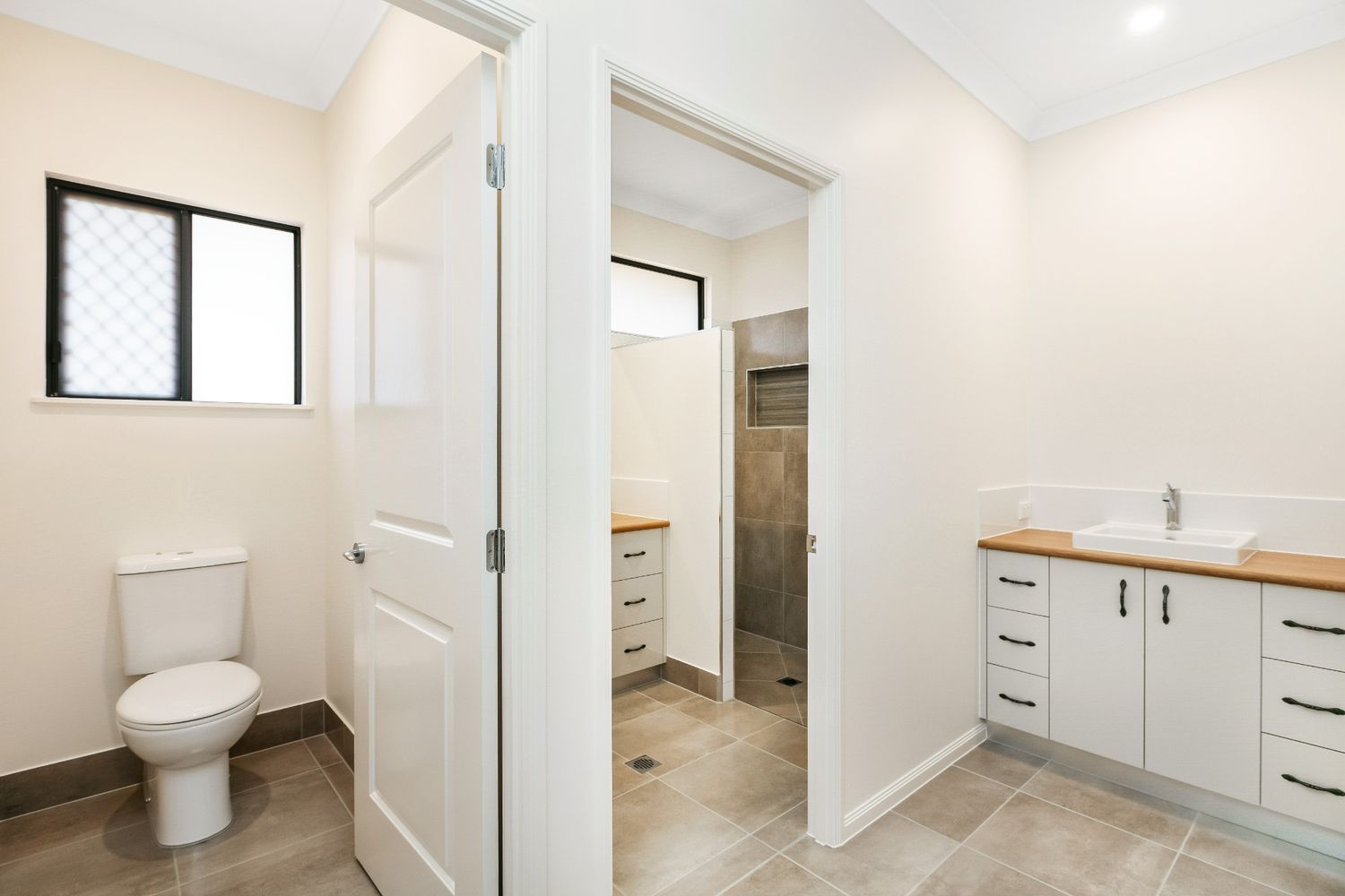 A Bathroom With a Toilet, Sink, and Window — Ashlee Jones Homes in Gordonvale, QLD