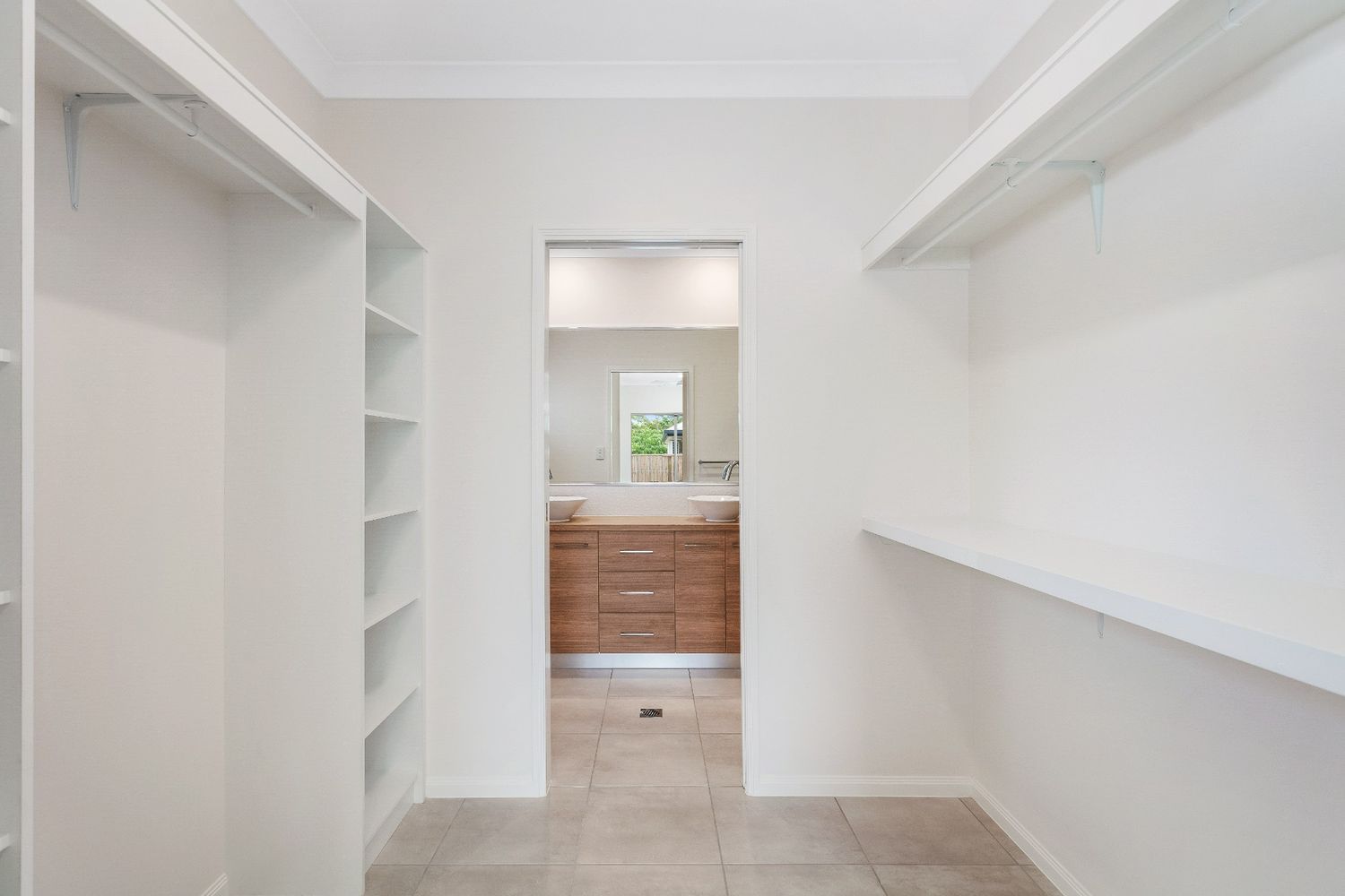 A Walk in Closet With Shelves and a Bathroom in the Background — Ashlee Jones Homes in Gordonvale, QLD
