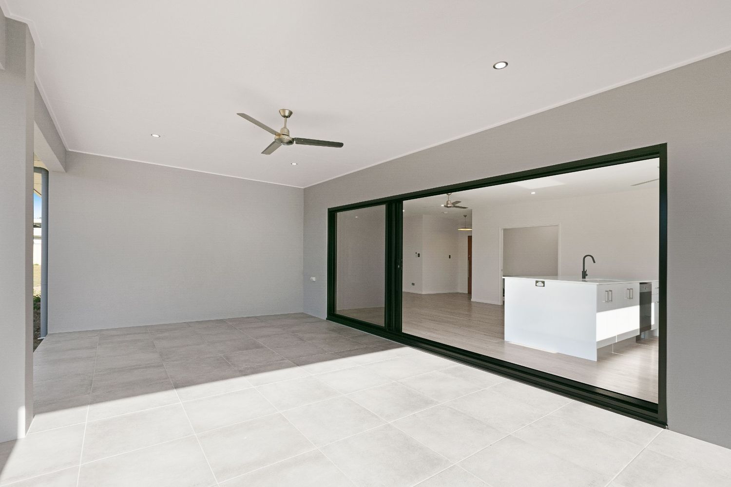 An Empty Room With Sliding Glass Doors and a Ceiling Fan — Ashlee Jones Homes in Gordonvale, QLD