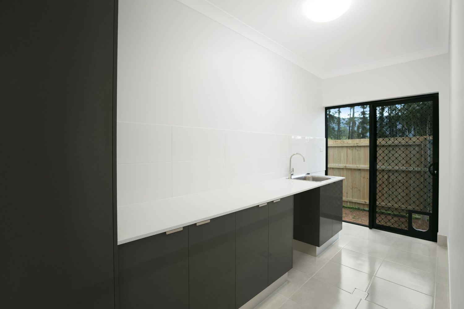 An Empty Kitchen With Black Cabinets and White Counter Tops — Ashlee Jones Homes in Gordonvale, QLD