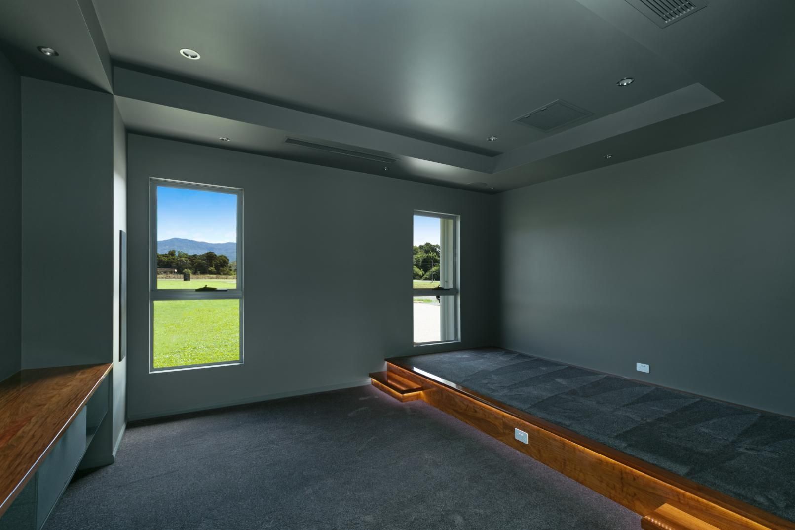An Empty Room With a Couch and Two Windows — Ashlee Jones Homes in Gordonvale, QLD
