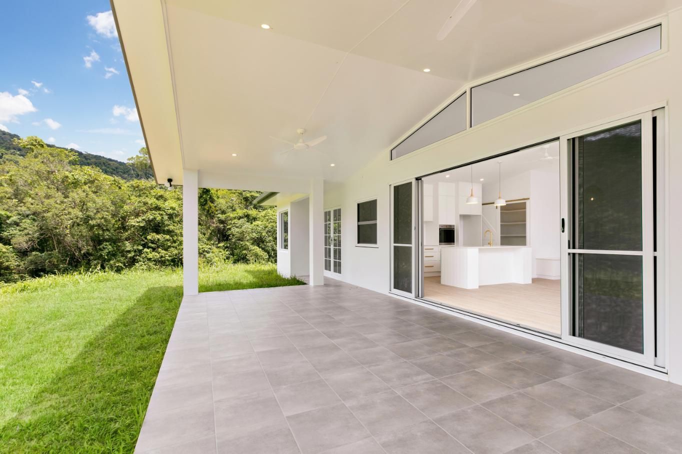 A Large White House With a Large Patio and Sliding Glass Doors — Ashlee Jones Homes in Gordonvale, QLD