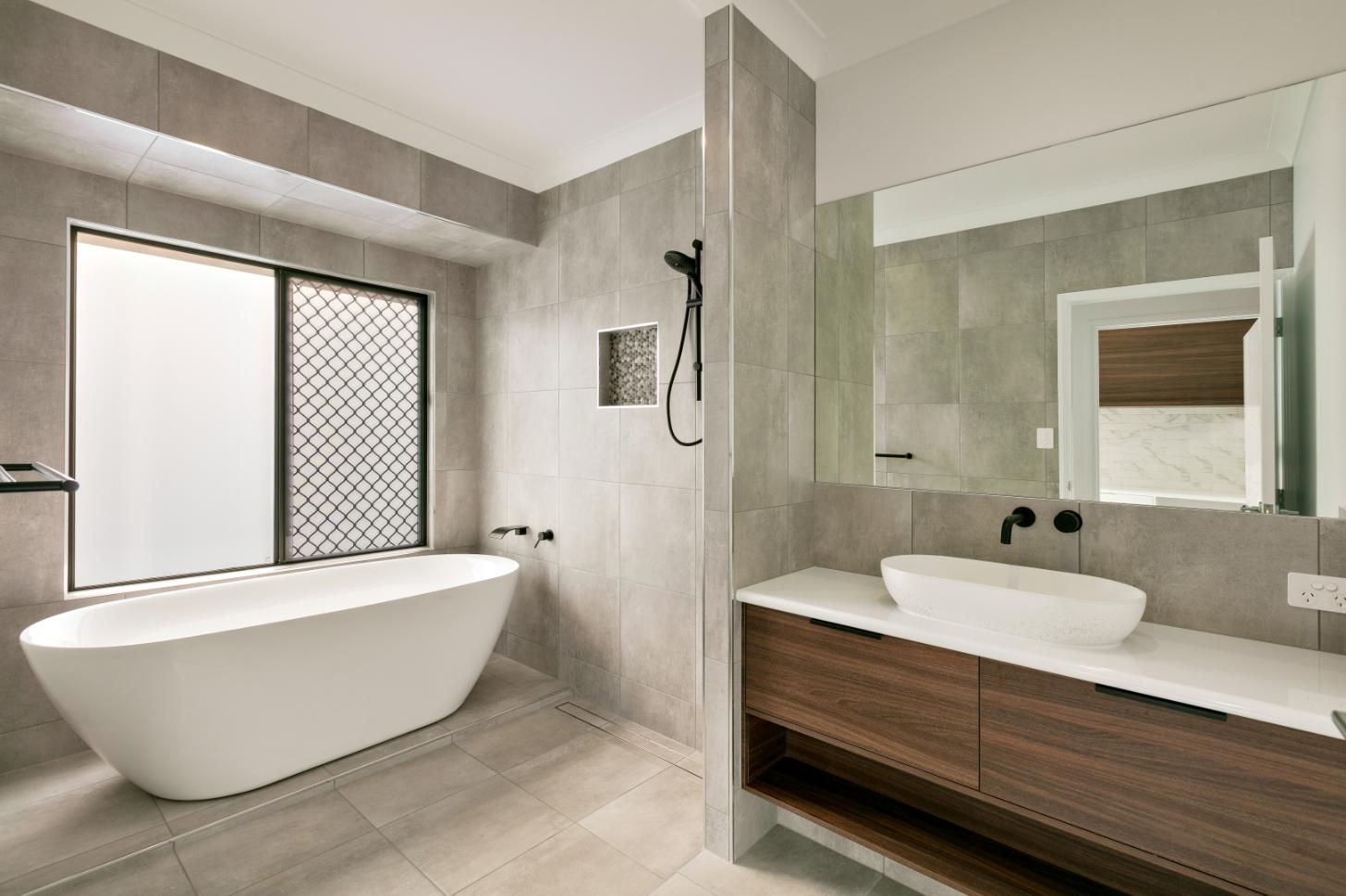 A Bathroom With a Bathtub, Sink, Mirror and Window — Ashlee Jones Homes in Gordonvale, QLD