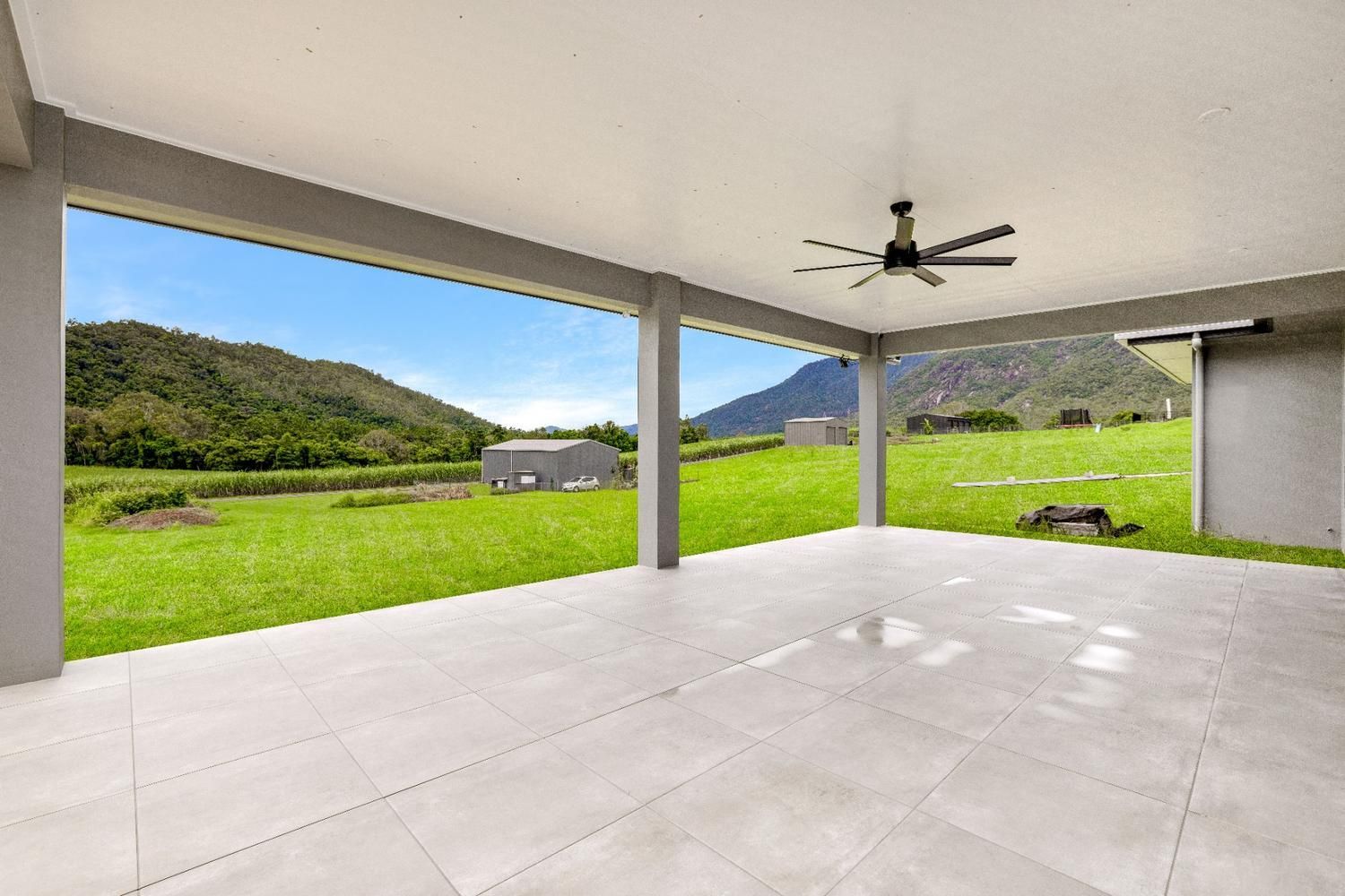 An Empty Patio With a Ceiling Fan and a View of a Grassy Field — Ashlee Jones Homes in Gordonvale, QLD