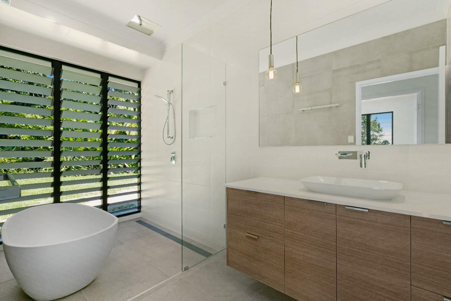 A Bathroom With a Tub, Sink, Mirror and Walk in Shower — Ashlee Jones Homes in Gordonvale, QLD