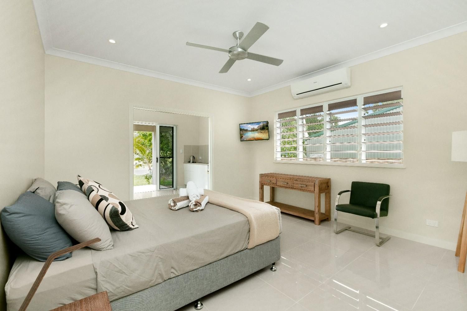 A Bedroom With a Bed, Chair, Table and Ceiling Fan — Ashlee Jones Homes in Gordonvale, QLD