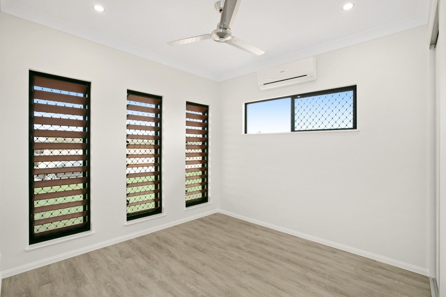 An Empty Room With Two Windows and a Ceiling Fan — Ashlee Jones Homes in Gordonvale, QLD